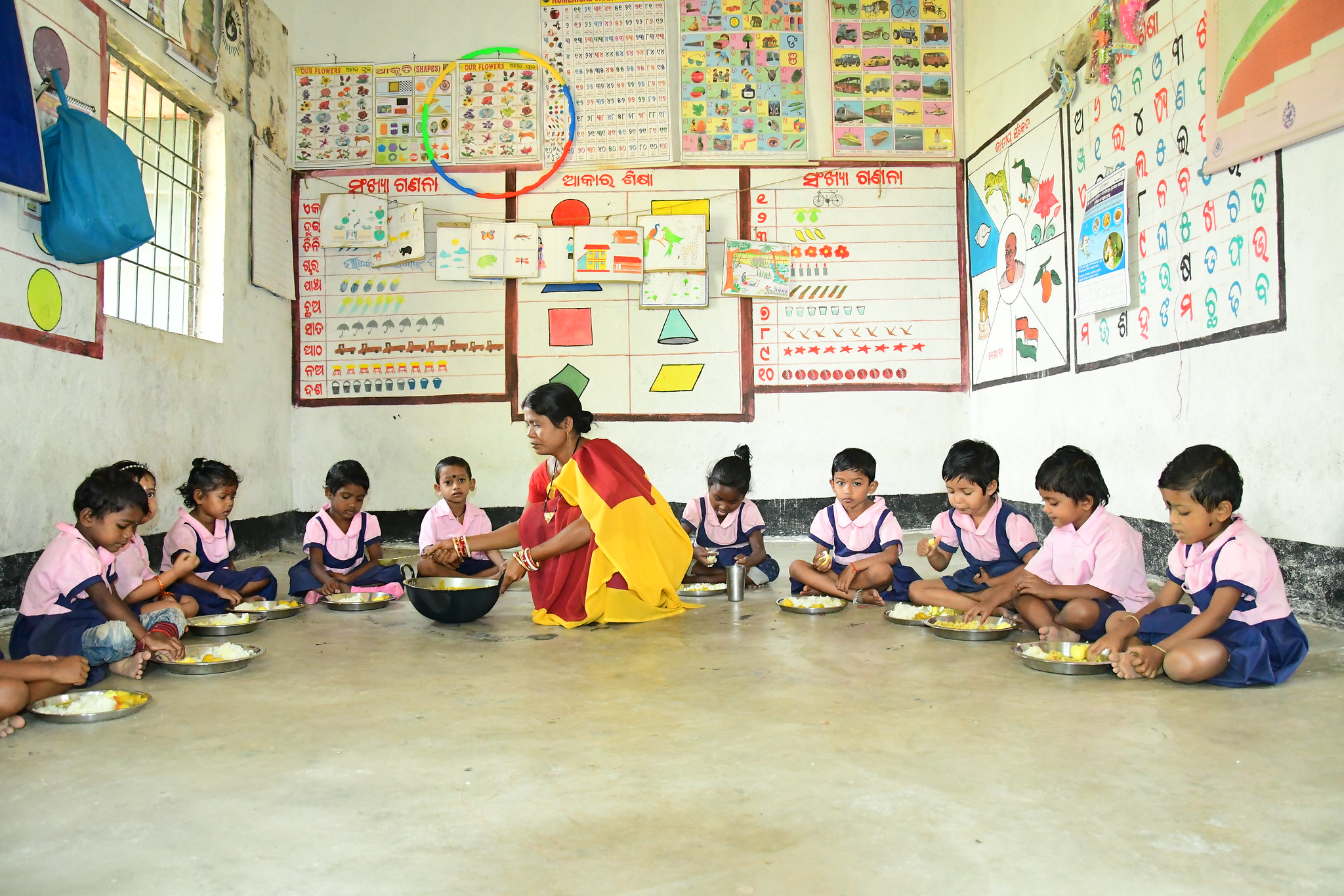 Children at the Bangabandha Anganwadi center (childcare center) enjoying small fish in hot cooked meals as part of the of Supplementary Nutrition Programme