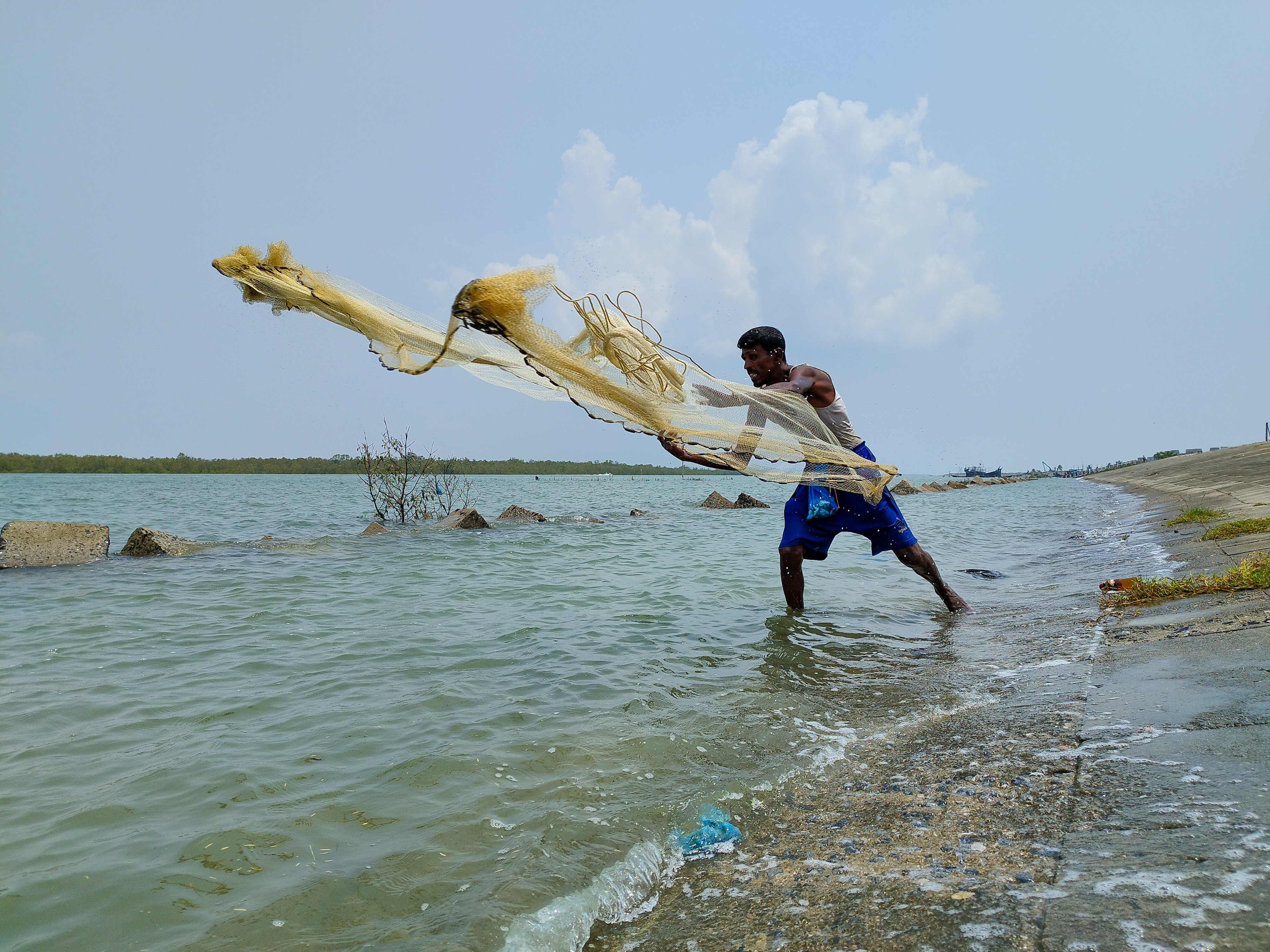 A fisher, currently residing at the Khuruskhul Cyclone Centre, Coxs’s Bazar, casts a hand-thrown net into the Moheshkhali-Cox’s Bazar channel. Despite seasonal restrictions on deep-sea commercial fishing, small-scale subsistence casting remains a vital means of survival for displaced residents. Credit: Hamid Hossen