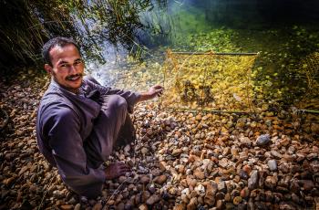 A farmer posing while holding a trap in a fish farm in El-Shahama, Wadi El-Sa’ayda, Edfu, Egypt.  Photo by Sara Fouad.